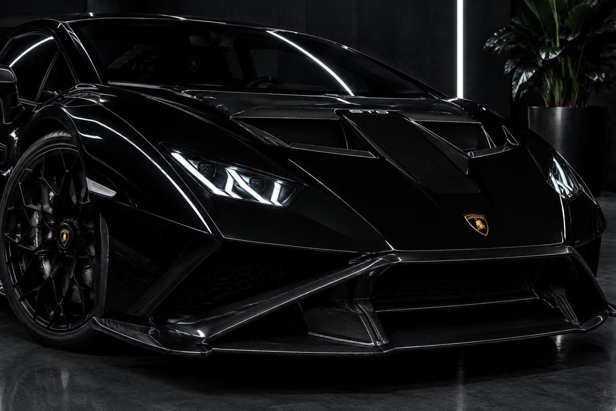 Front corner of a black Lamborghini Huracán STO with its Y-shaped headlight and polished paint
