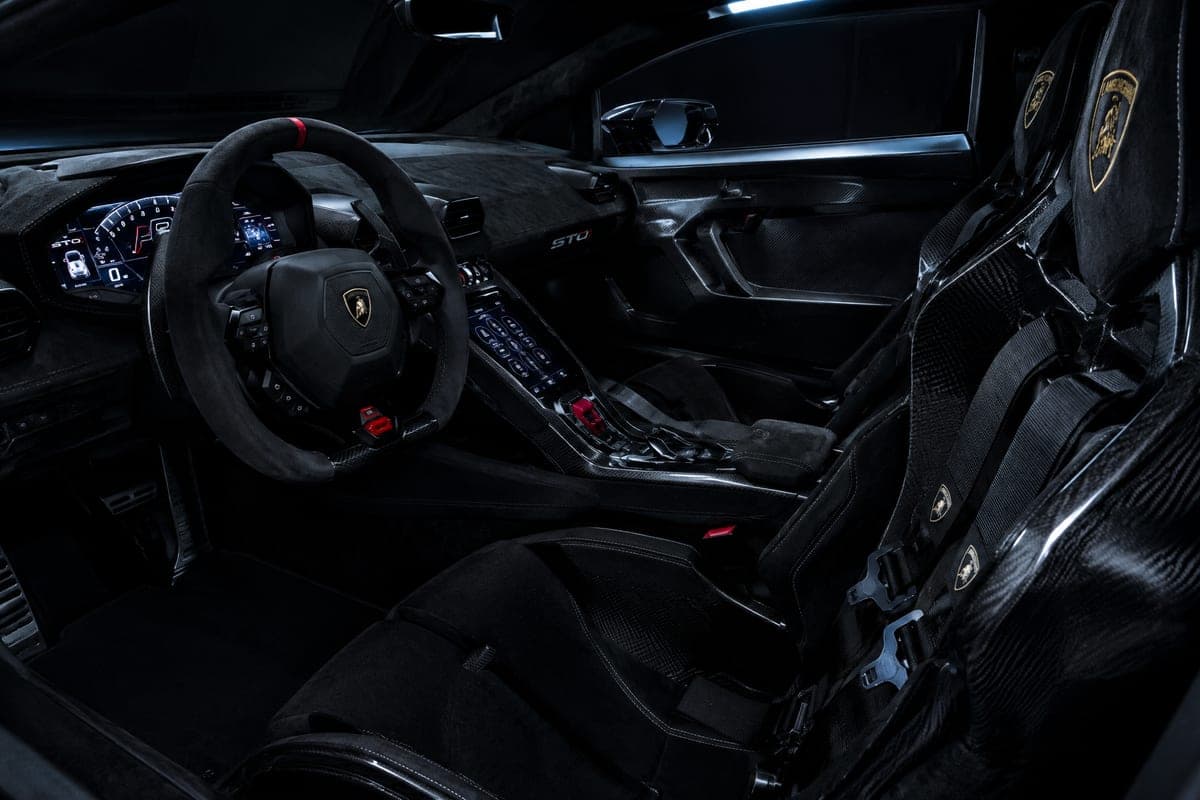 Carbon and Alcantara cabin of a Lamborghini Huracán STO with a glowing instrument display